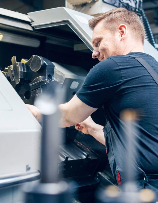 Experienced worker changing tool setup of lathe machine on the factory floor