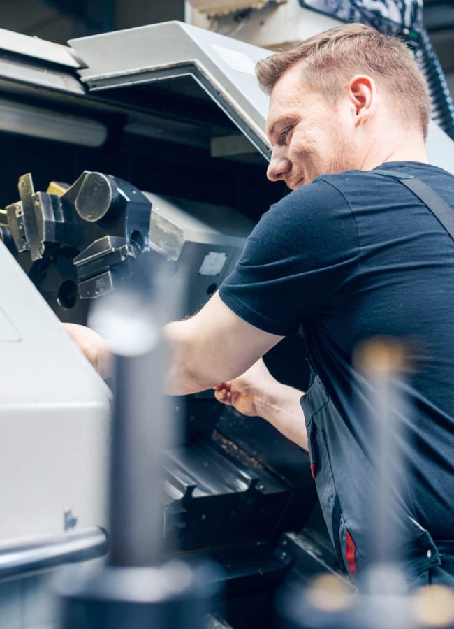 Experienced worker changing tool setup of lathe machine on the factory floor